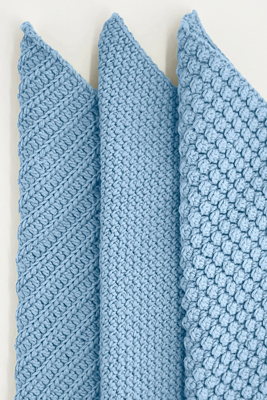 Three blue textured towels stacked on a white background