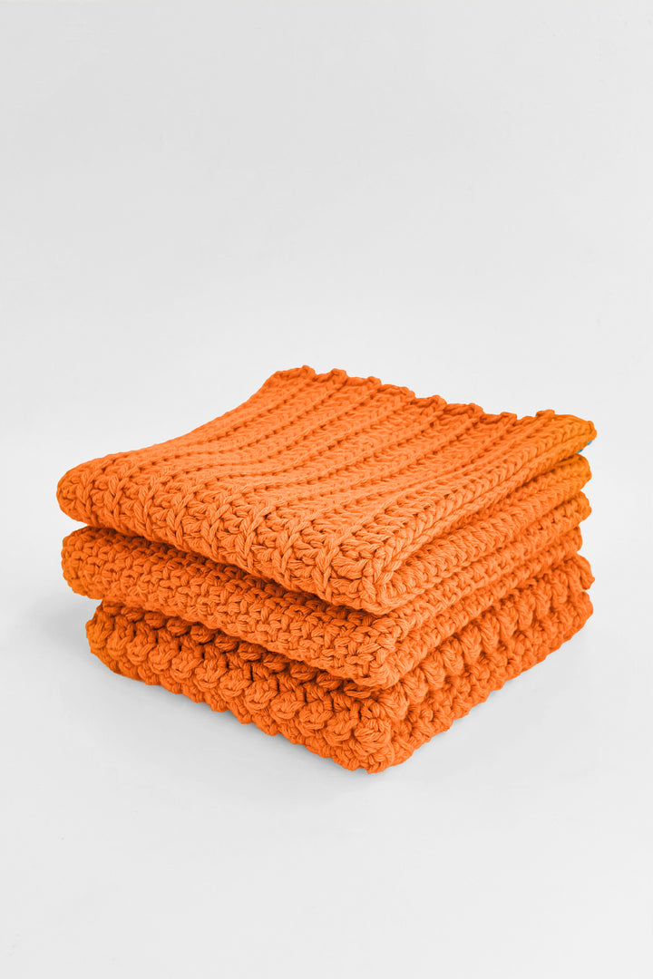 Stack of orange textured towels on a light gray background