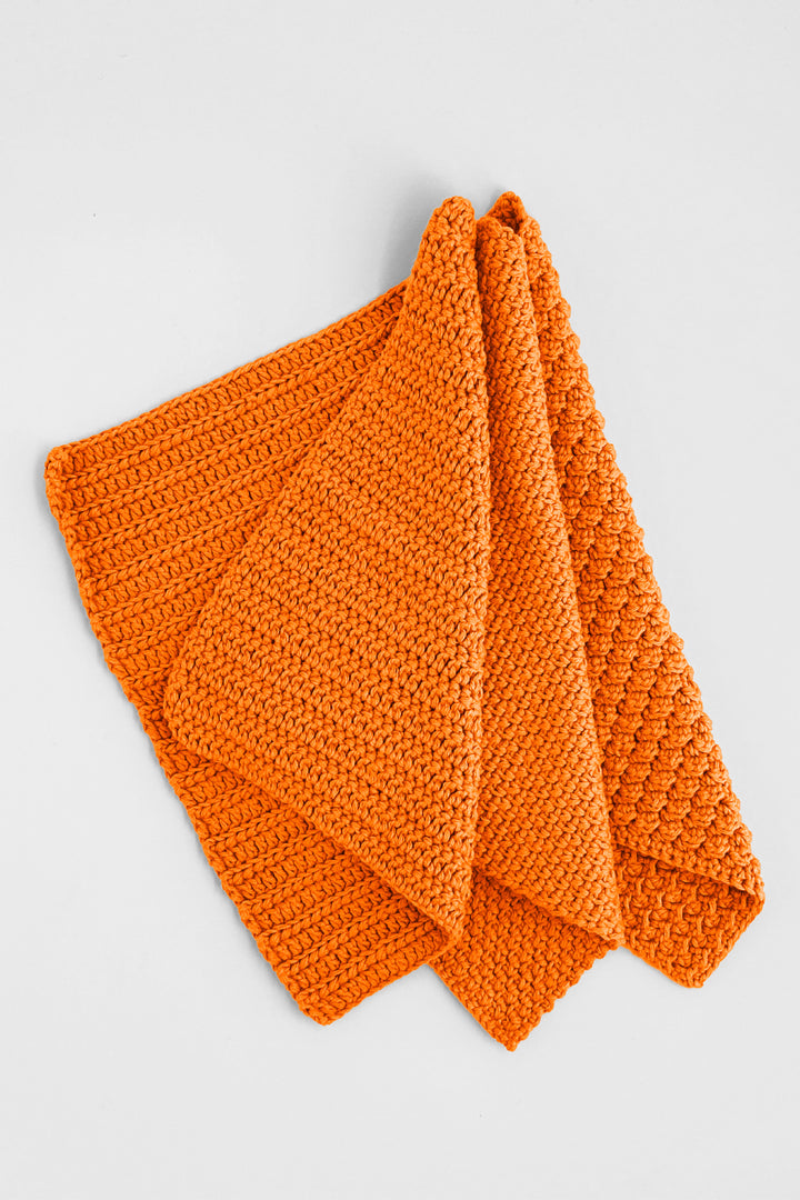 Orange crochet towels on a light gray background