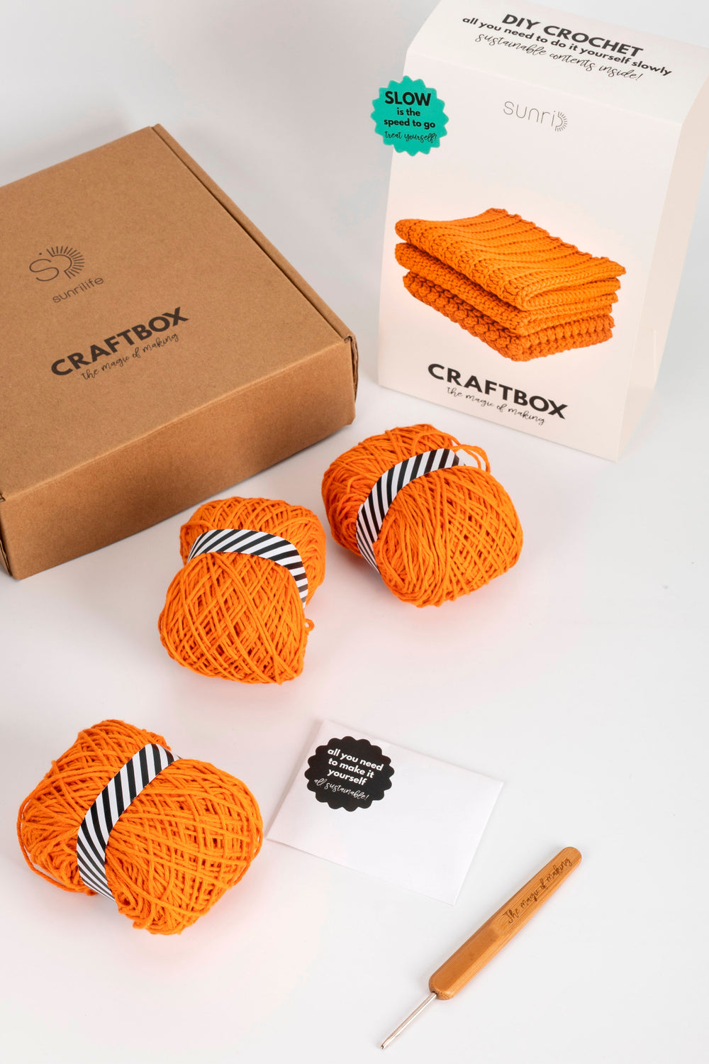 Craftbox with orange yarn and crochet hook on a white background