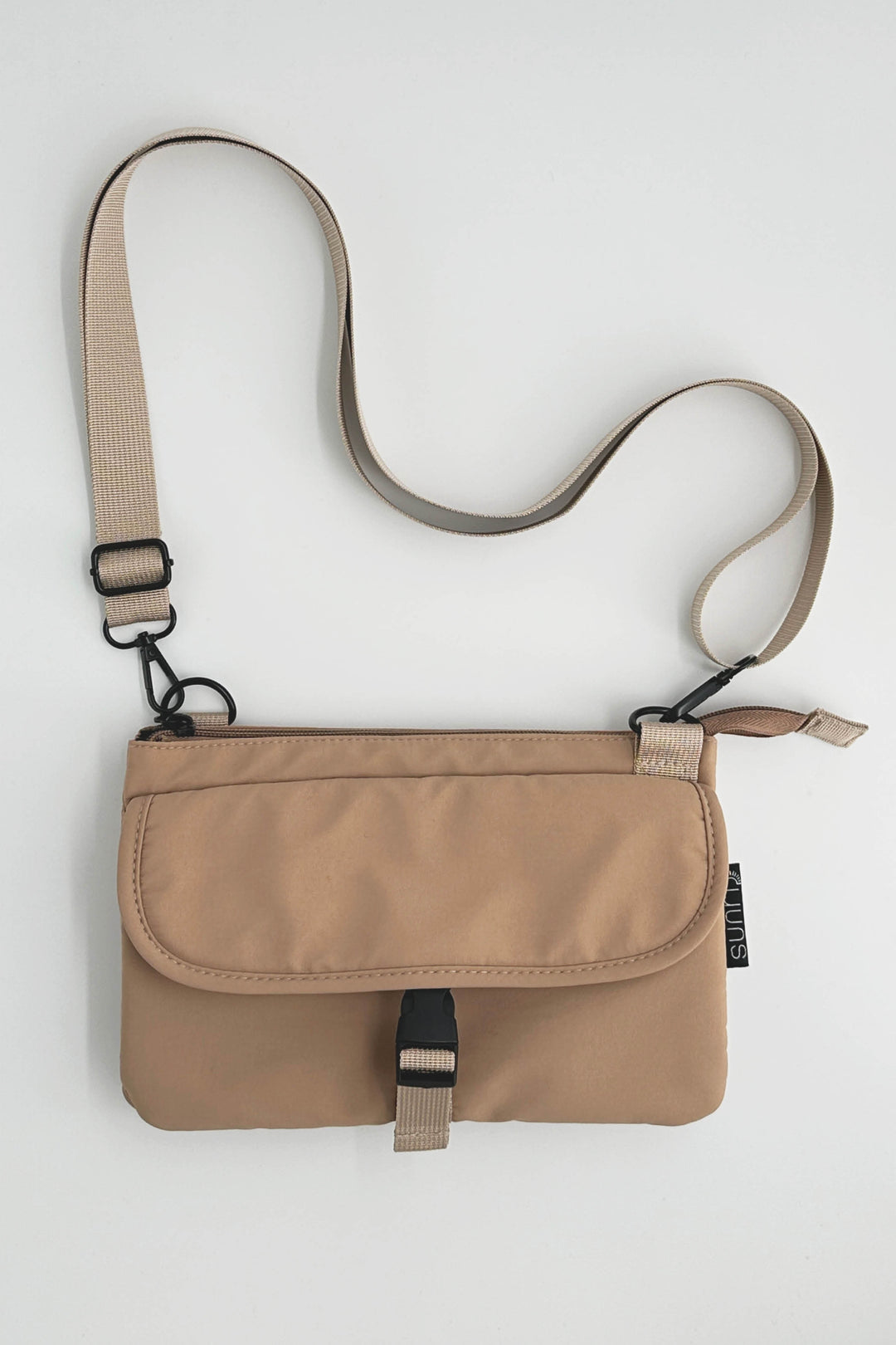 Beige crossbody bag with a strap on a light gray background