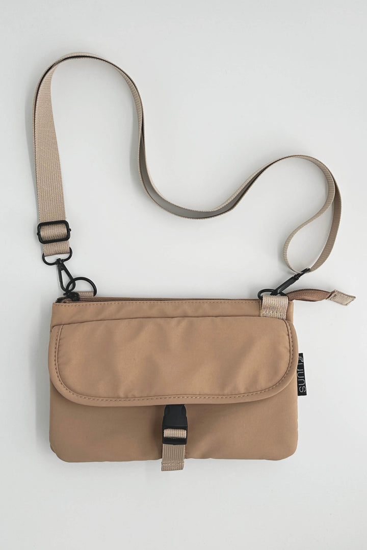Beige crossbody bag with a strap on a light gray background
