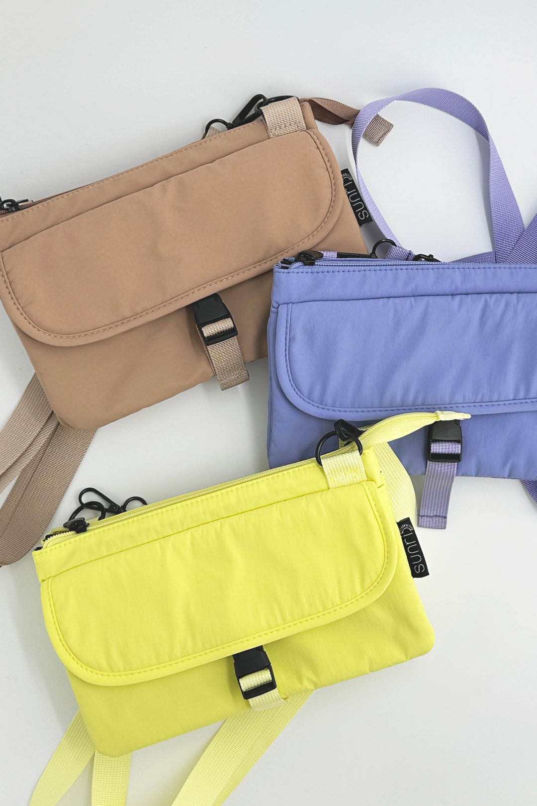 Three bags in beige, purple, and yellow on a white background