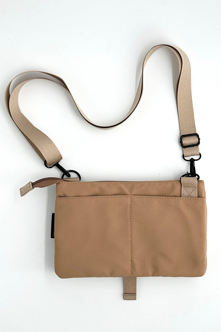 Tan crossbody bag with a strap on a white background