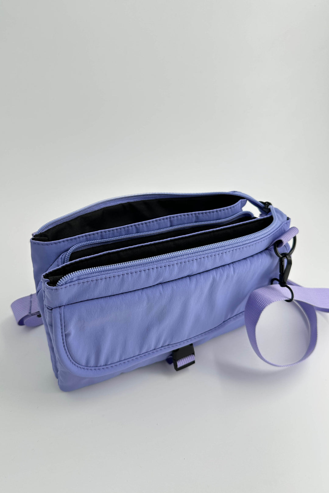 Purple waist bag with a keychain on a light gray background