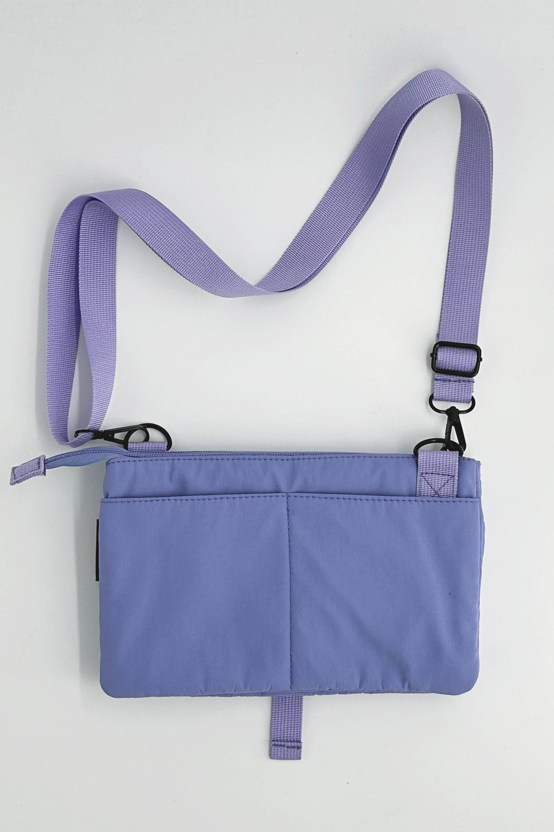 Purple crossbody bag with a strap on a light gray background