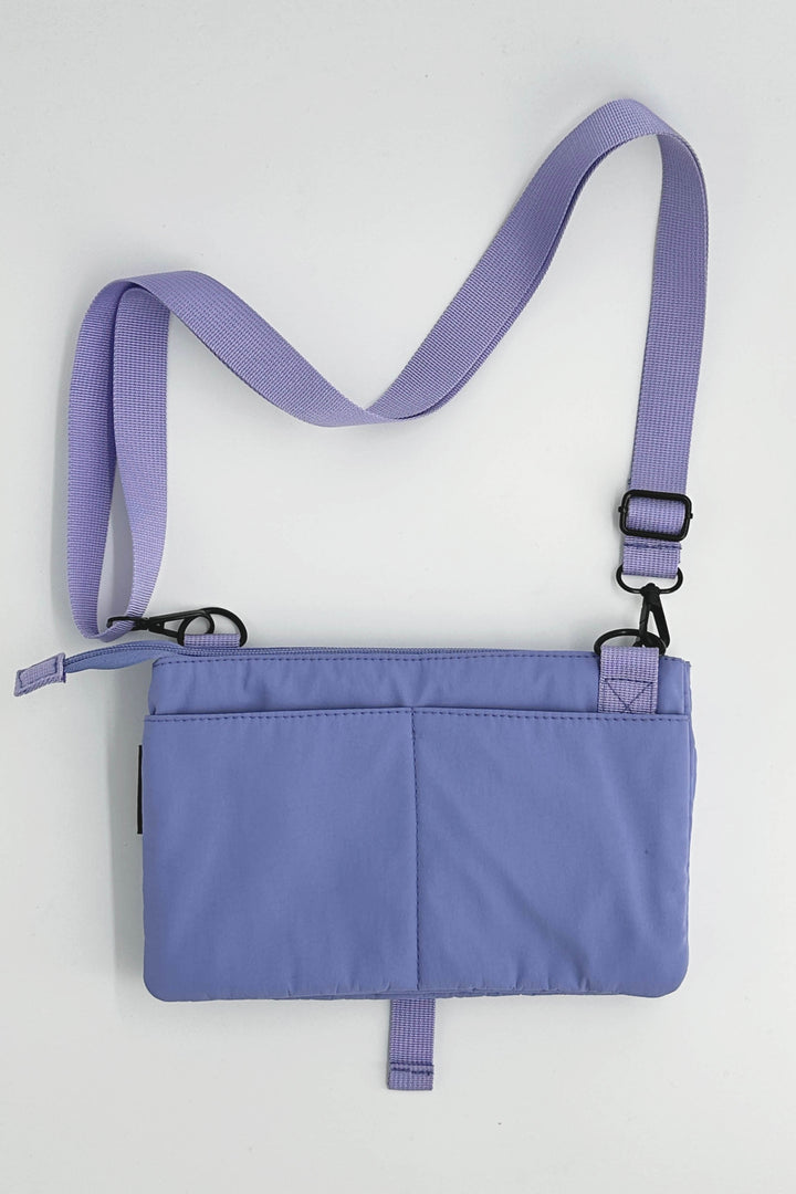 Purple crossbody bag with a strap on a light gray background