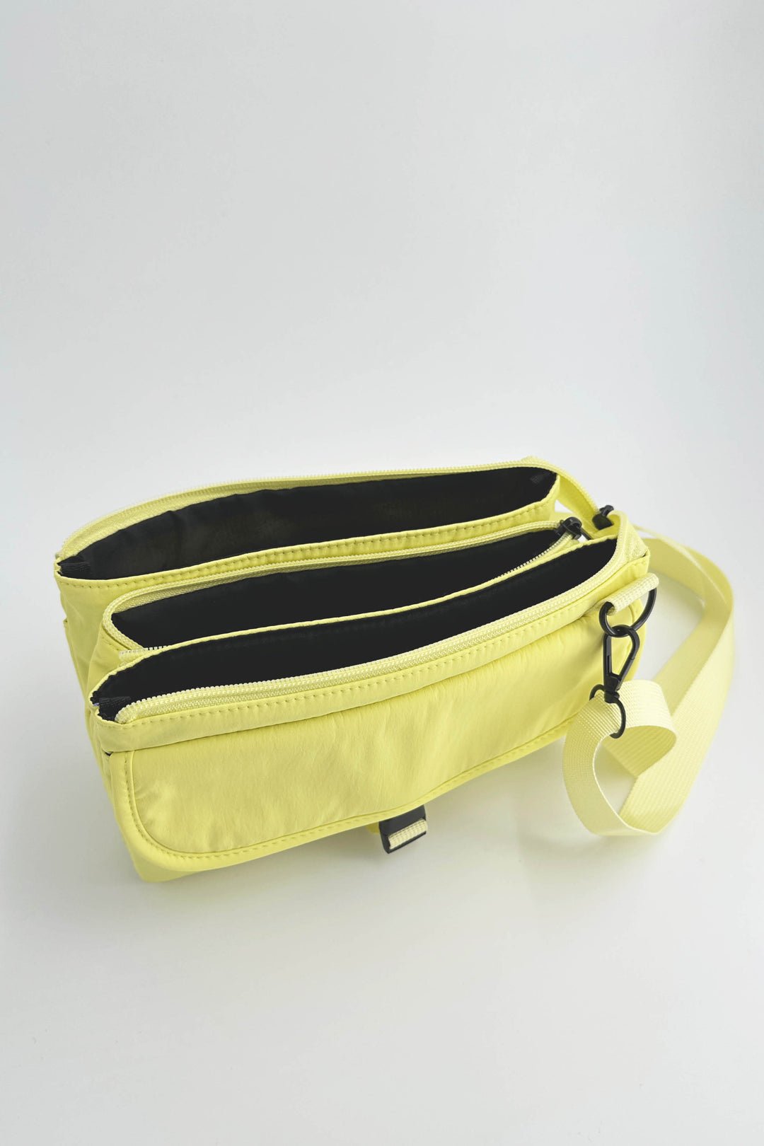 Yellow crossbody bag with black interior on a light gray background