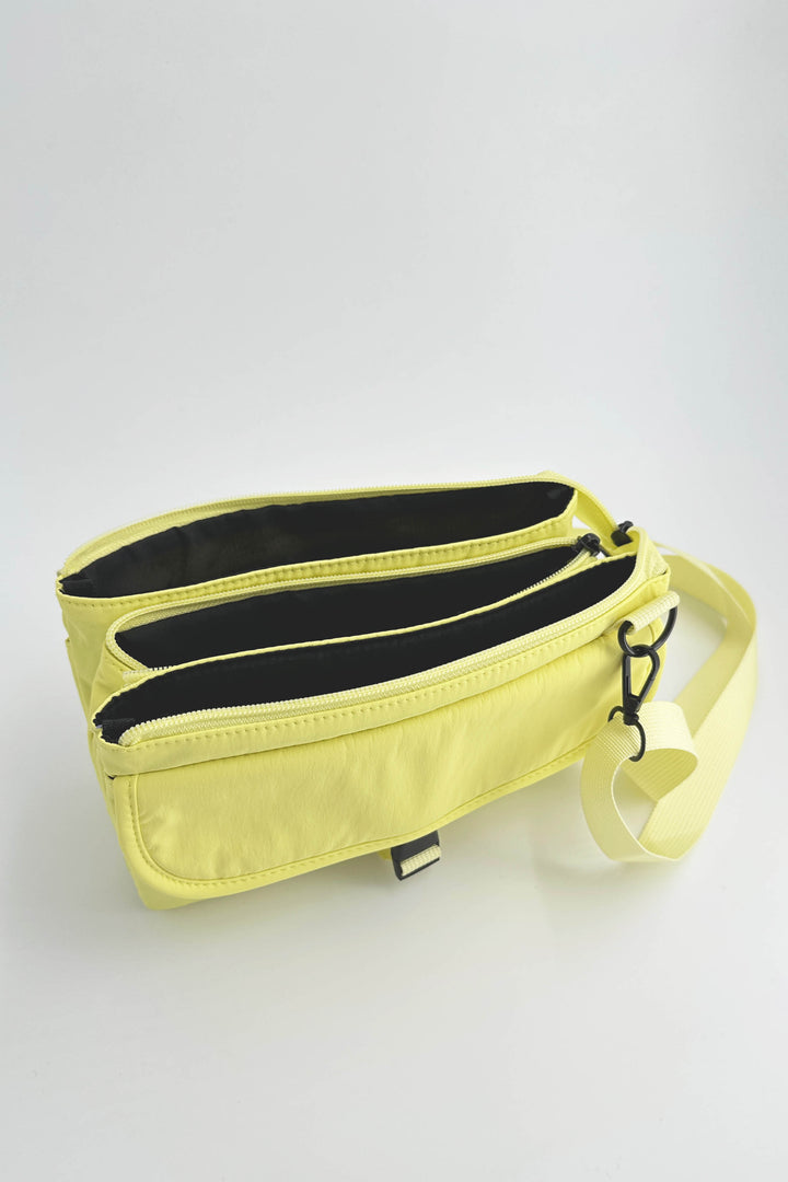 Yellow crossbody bag with black interior on a light gray background