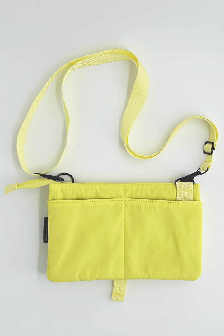 Yellow crossbody bag with a strap on a light gray background