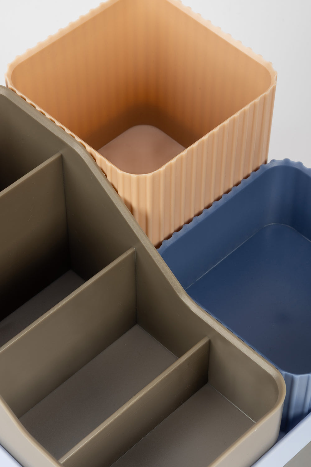 Set of three desk containers in beige, brown, and blue on a white background