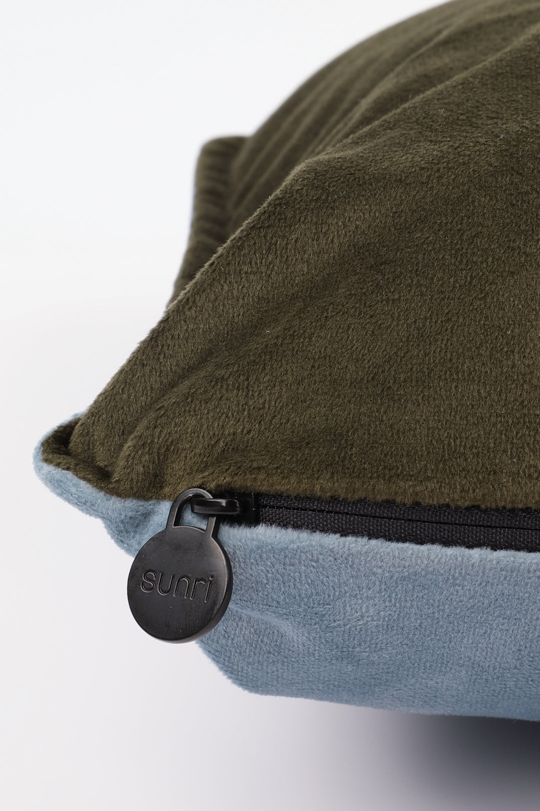 Close-up of a green and blue pillow with a zipper and 'Sunri' brand logo.