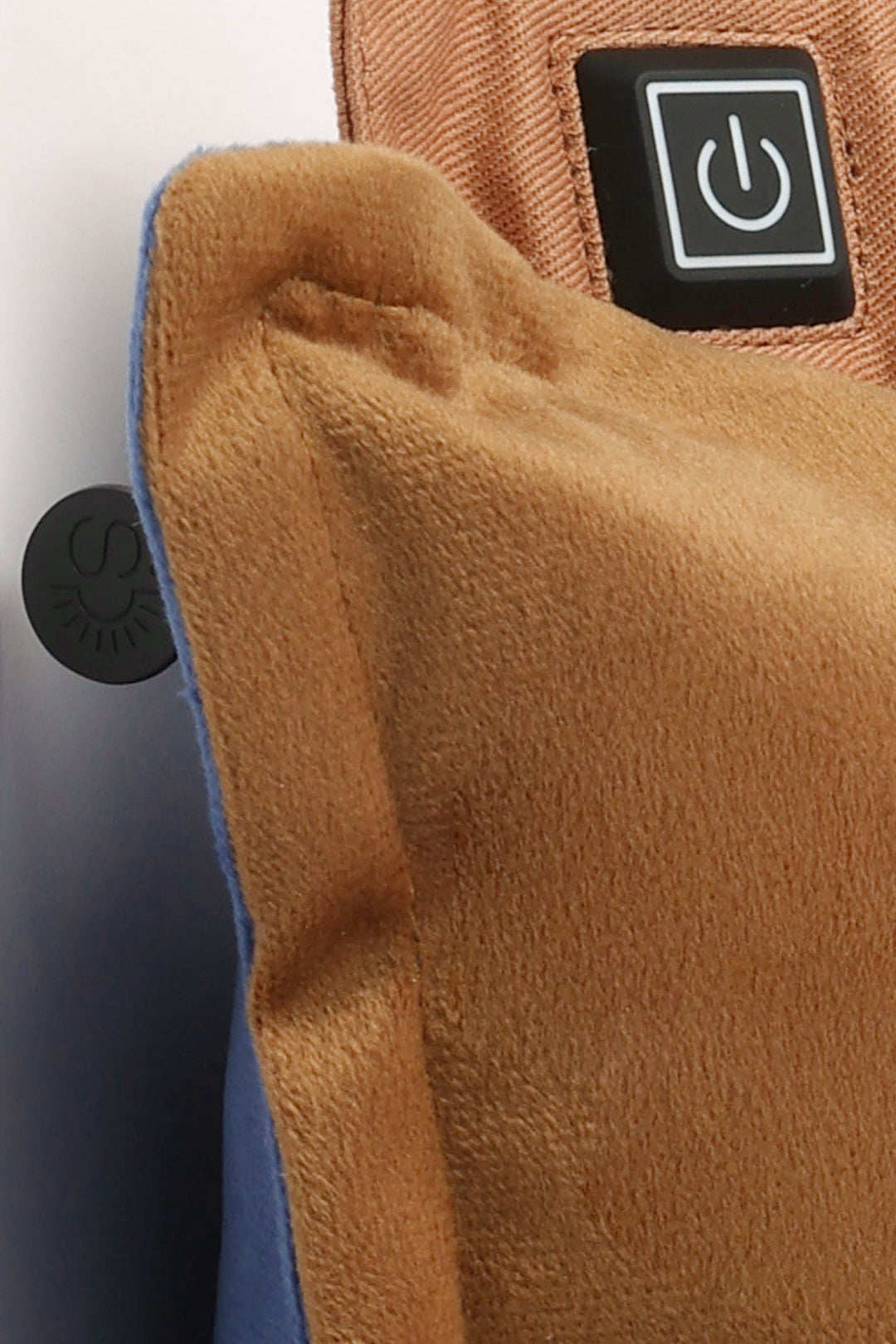 Close-up of a brown plush pillow with a power symbol button on a white background