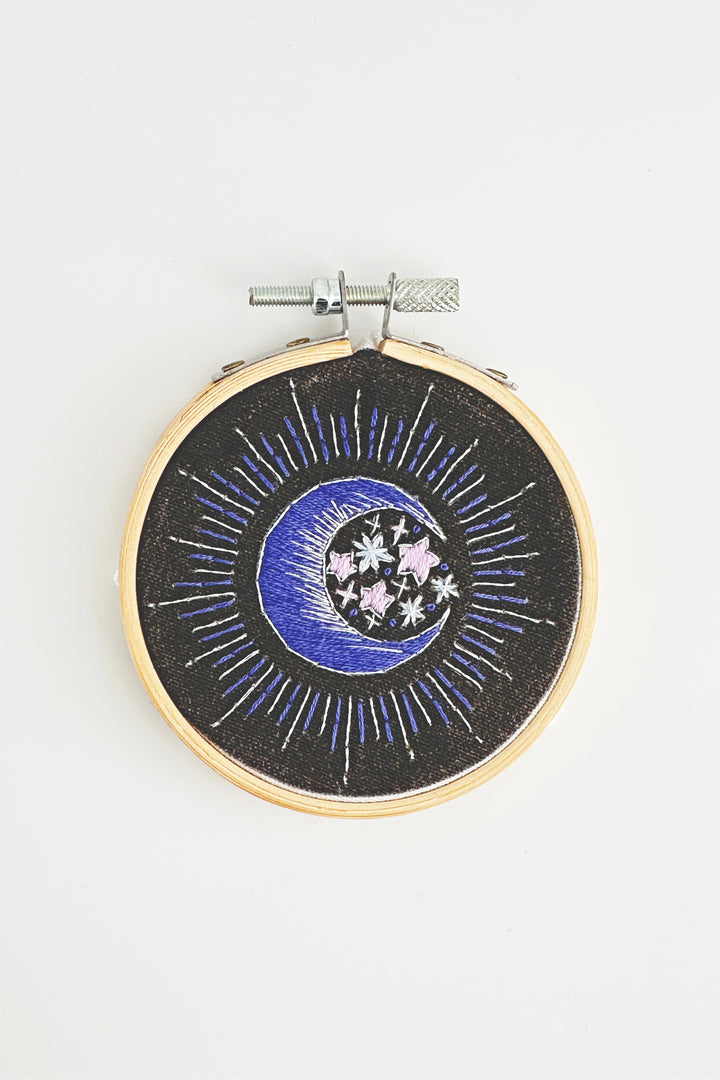Embroidery hoop with celestial design on a white background