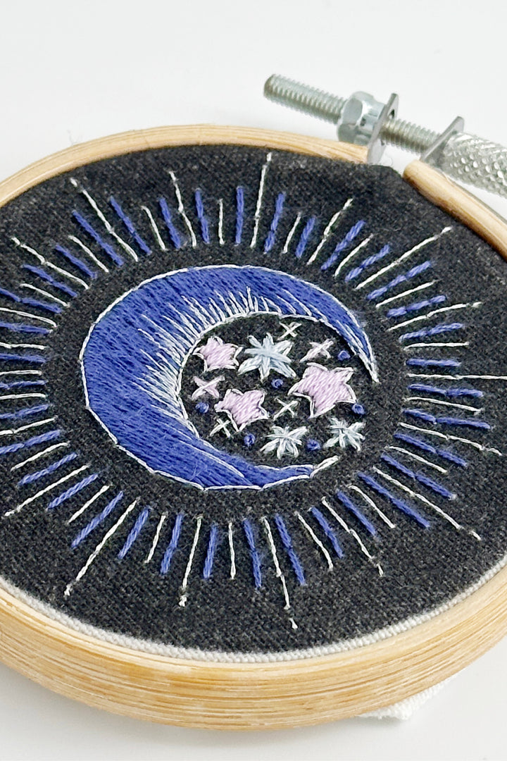 Embroidery hoop with blue and white celestia design on a black background