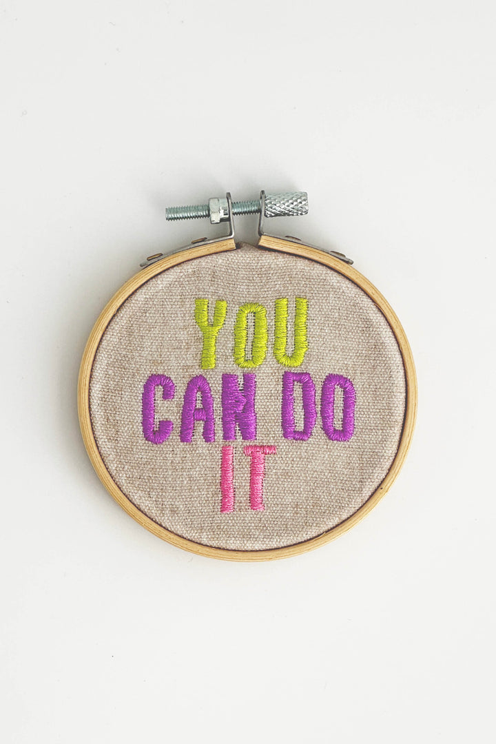 Embroidery hoop with 'You Can Do It' text in colorful thread on a white background