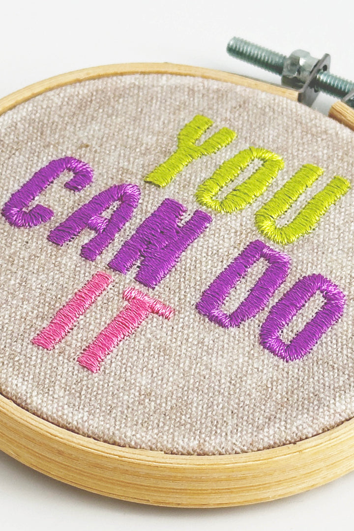 Embroidery hoop with 'You Can Do It' text in colorful thread on a white background