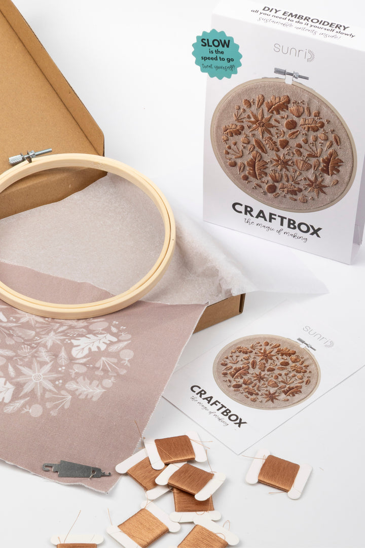 Sunri Craftbox DIY embroidery kit with wooden embroidery hoop, brown embroidery threads, floral design fabric and packaging box on a white background