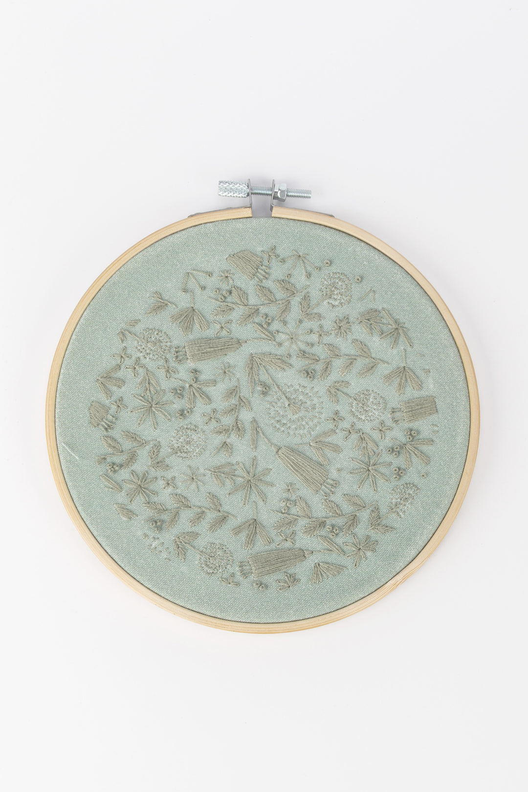Embroidery hoop with floral pattern on a light green fabric against a white background