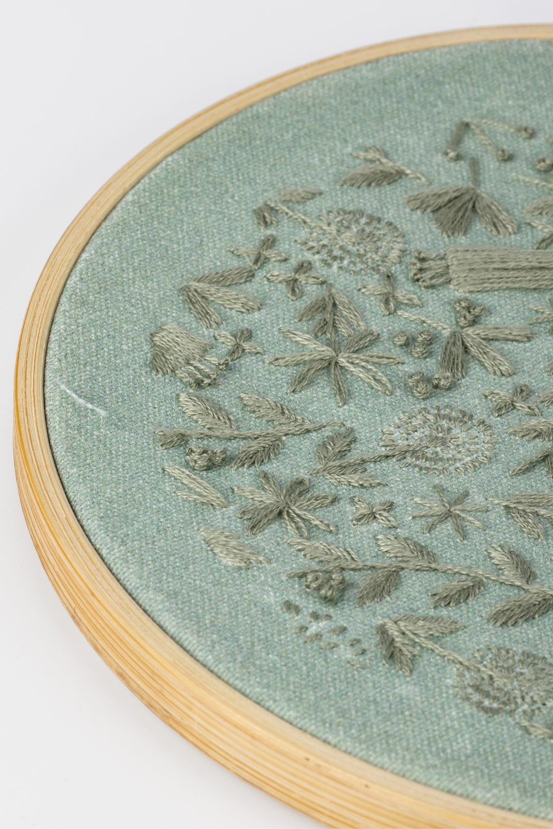 Embroidery hoop with floral pattern on a light green fabric background