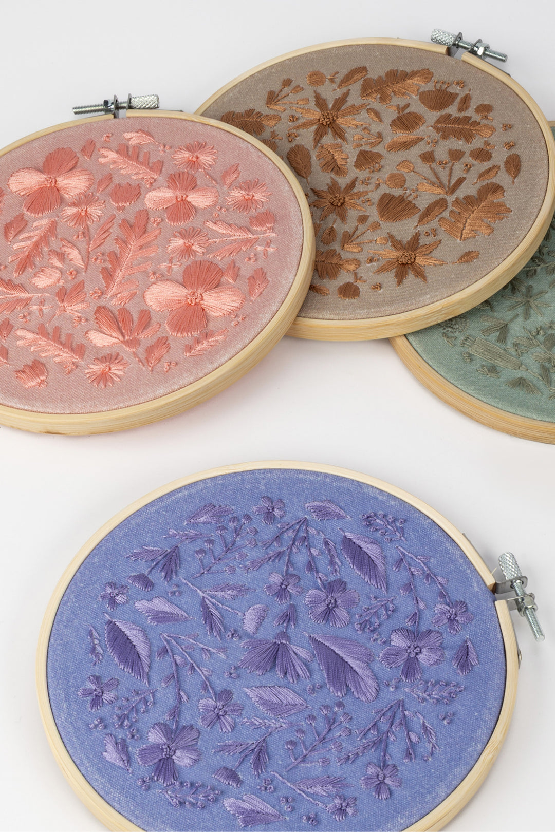 Four embroidery hoops with floral patterns on a white background