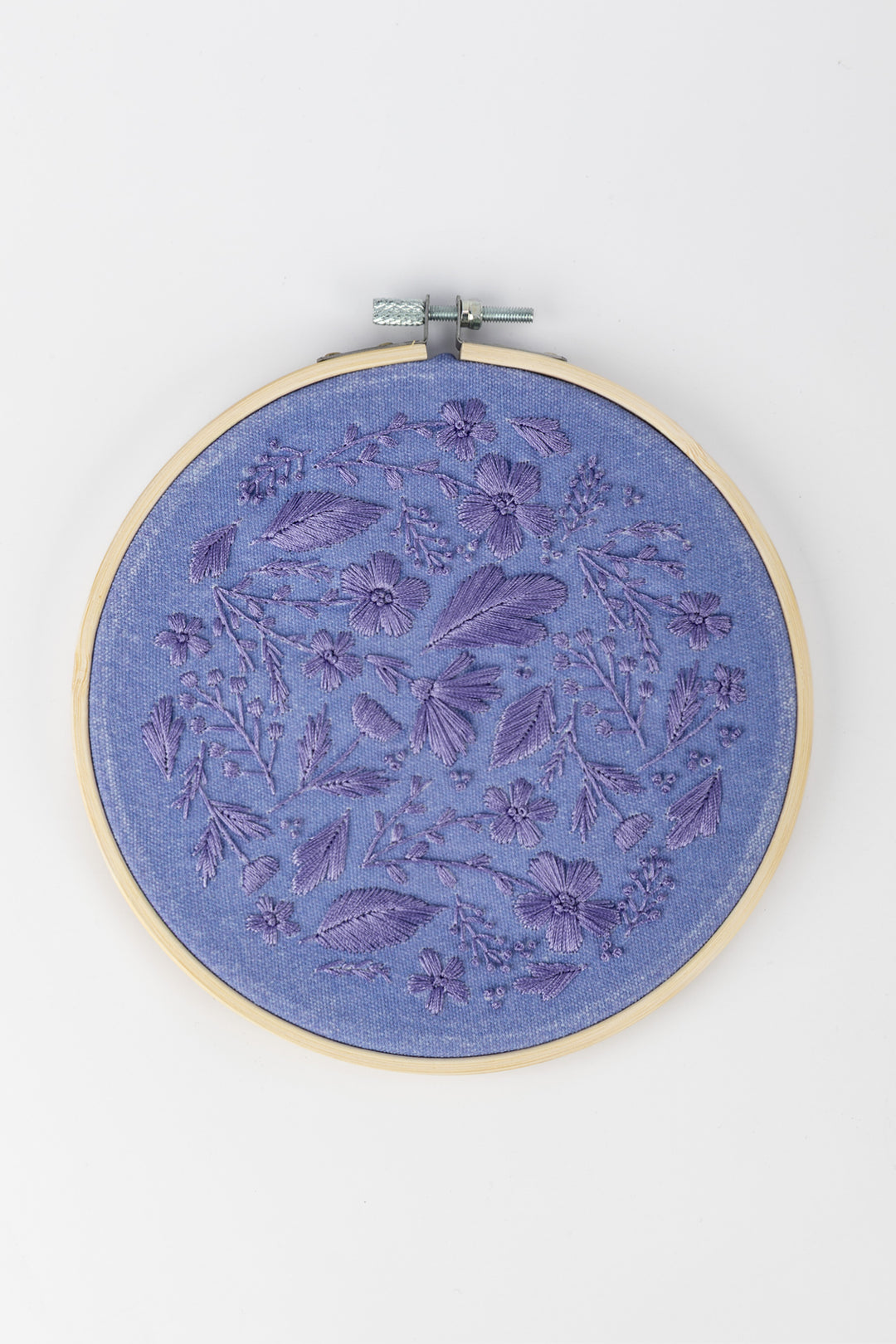 Sunri Craftbox embroidery hoop with purple floral embroidery design on blue fabric on a white background