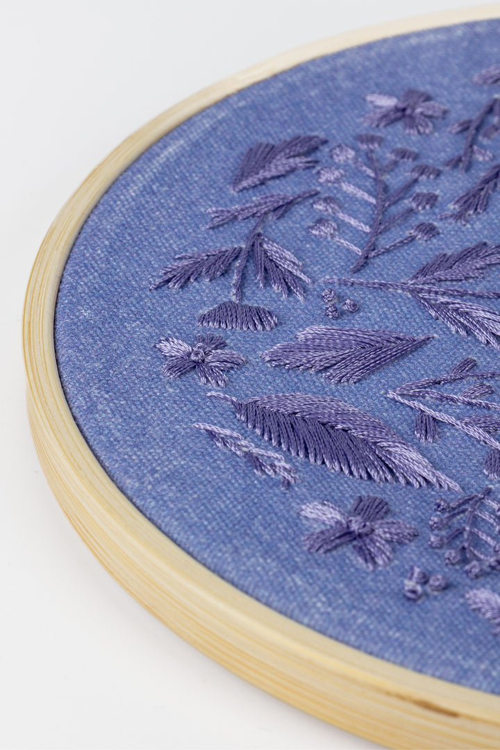 Embroidery hoop with purple floral pattern on a fabric background
