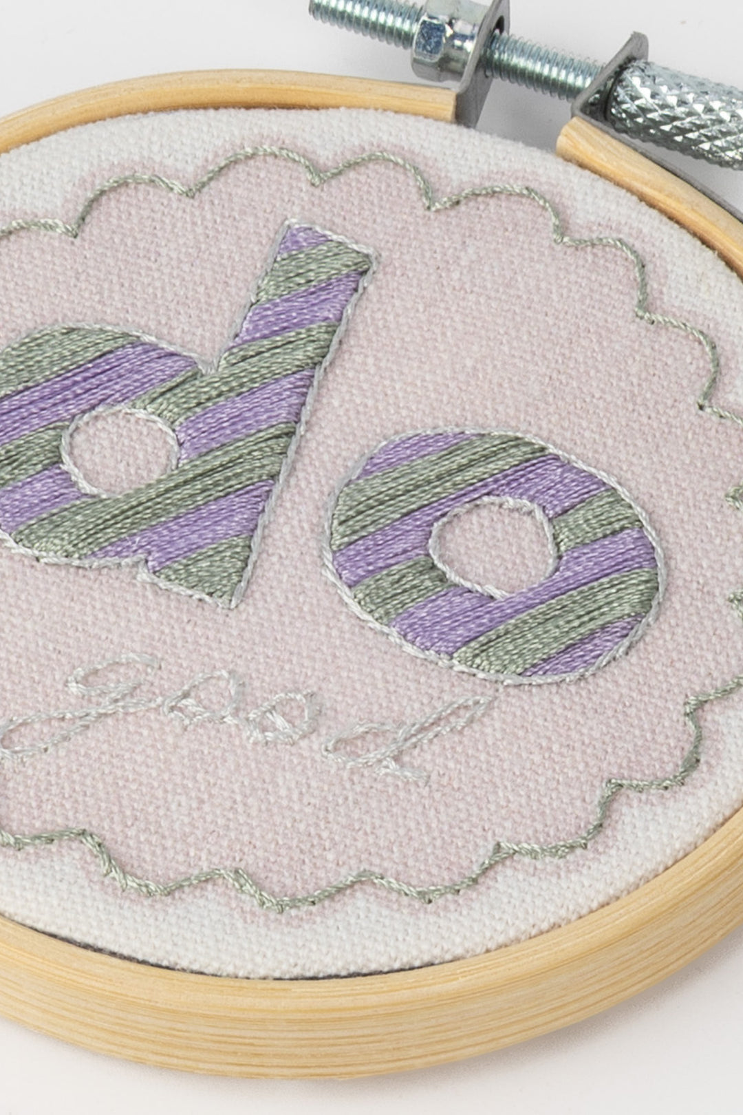 Embroidery hoop with a piece of embroidery featuring 'do good' text