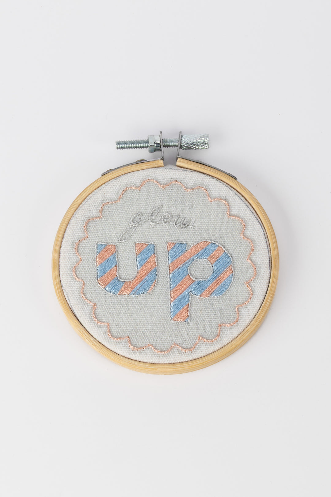 Embroidery hoop with 'glow up' text on a white background