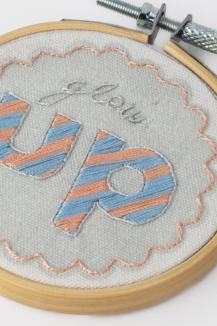 Embroidery hoop with striped 'glow up' text