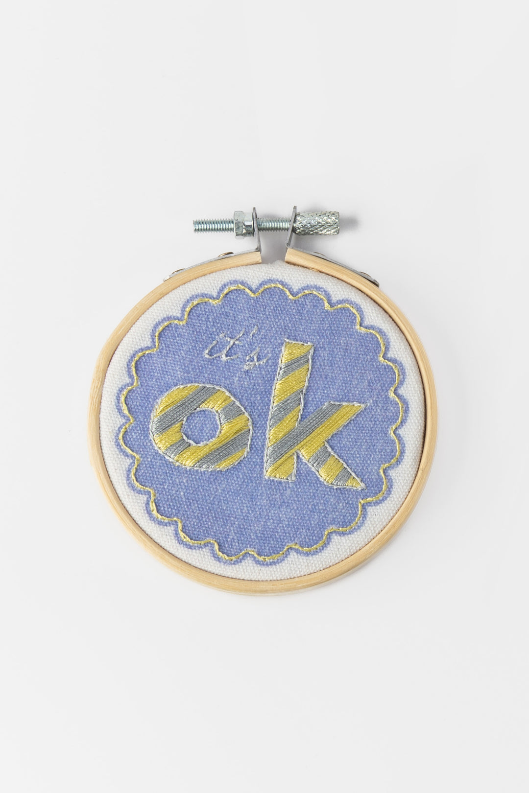 Embroidery hoop with 'it's ok' text on a blue background