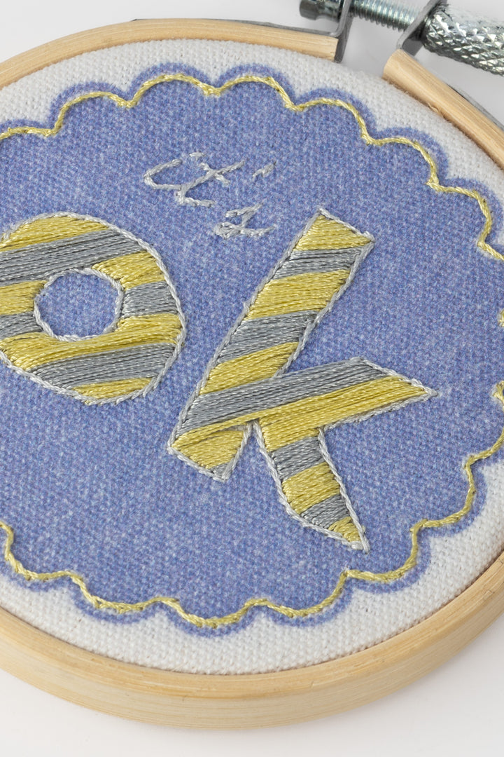 Embroidery hoop with 'It's OK' text on a blue background