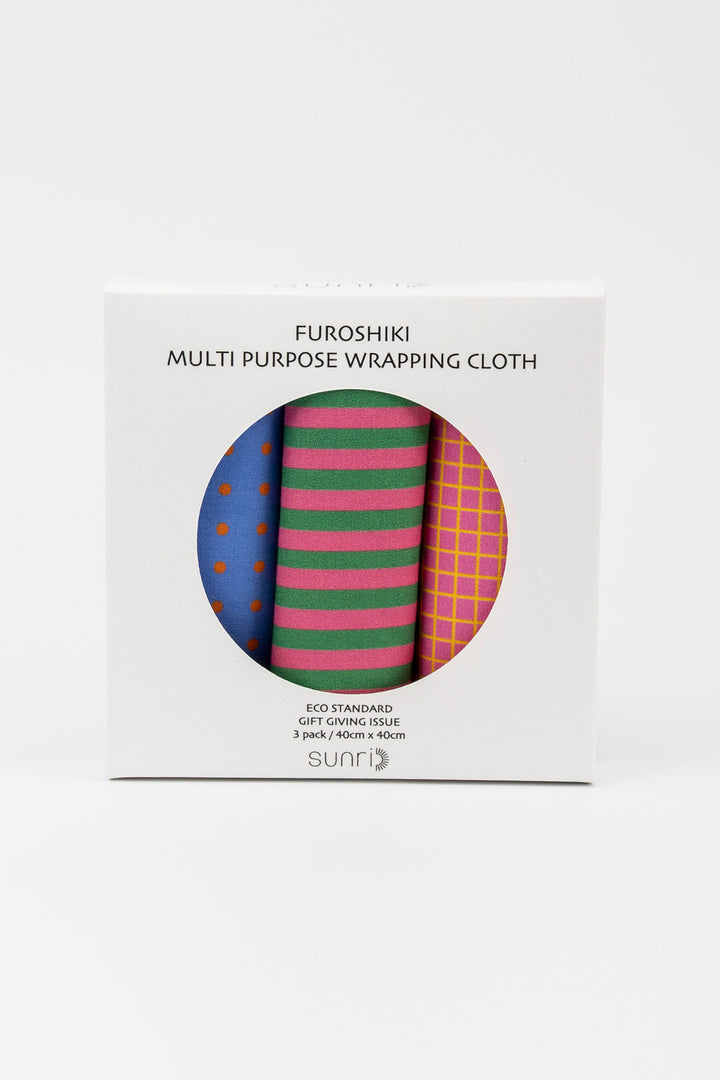 A white box of Furoshiki multi-purpose wrapping cloth with a circular cutout showing three rolled cloths: blue with orange dots, green and pink stripes, and pink and yellow plaid. The brand name 'sunr' is visible at the bottom of the box.