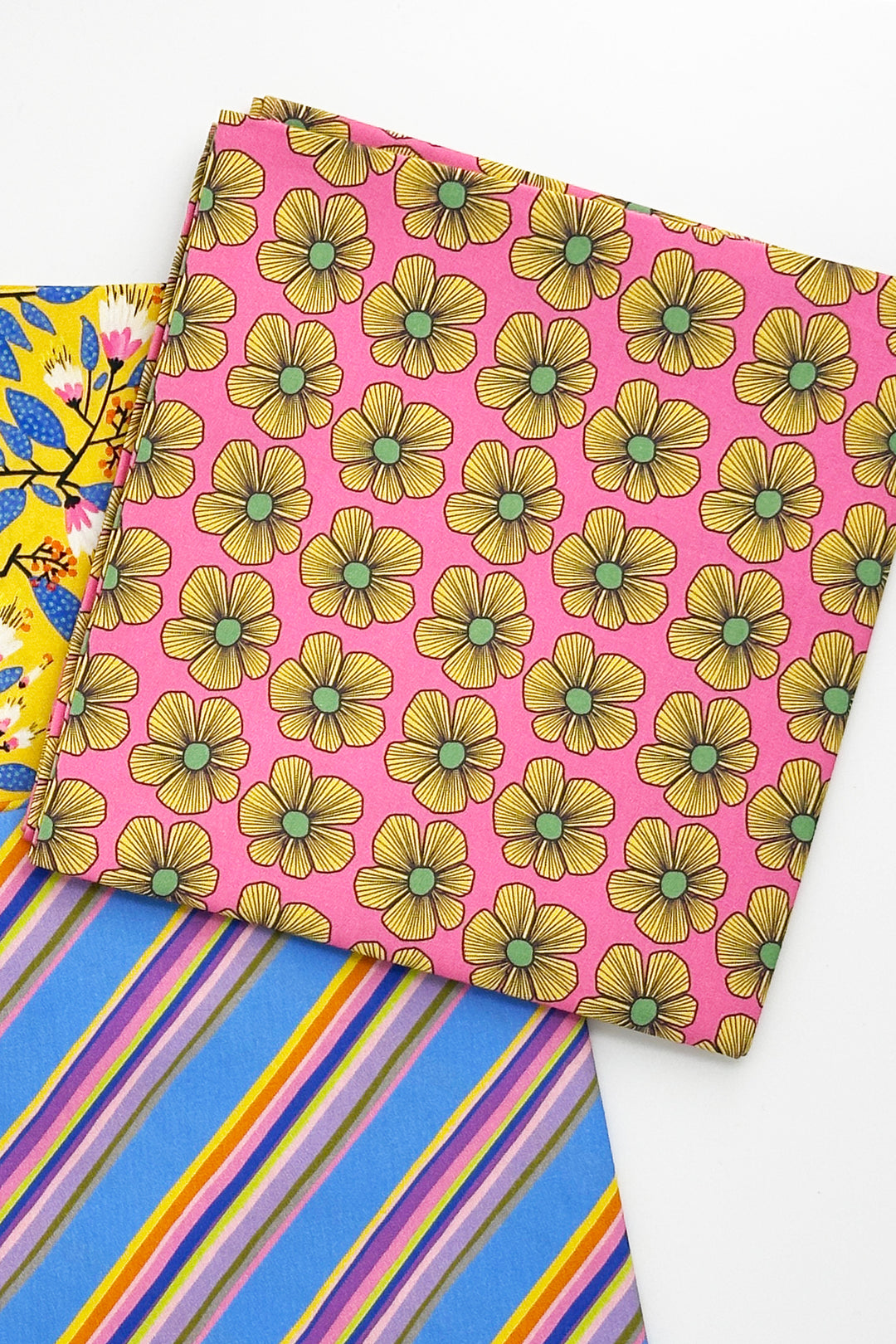 folded furoshiki wrapping cloth with pink floral print next to blue striped cloth