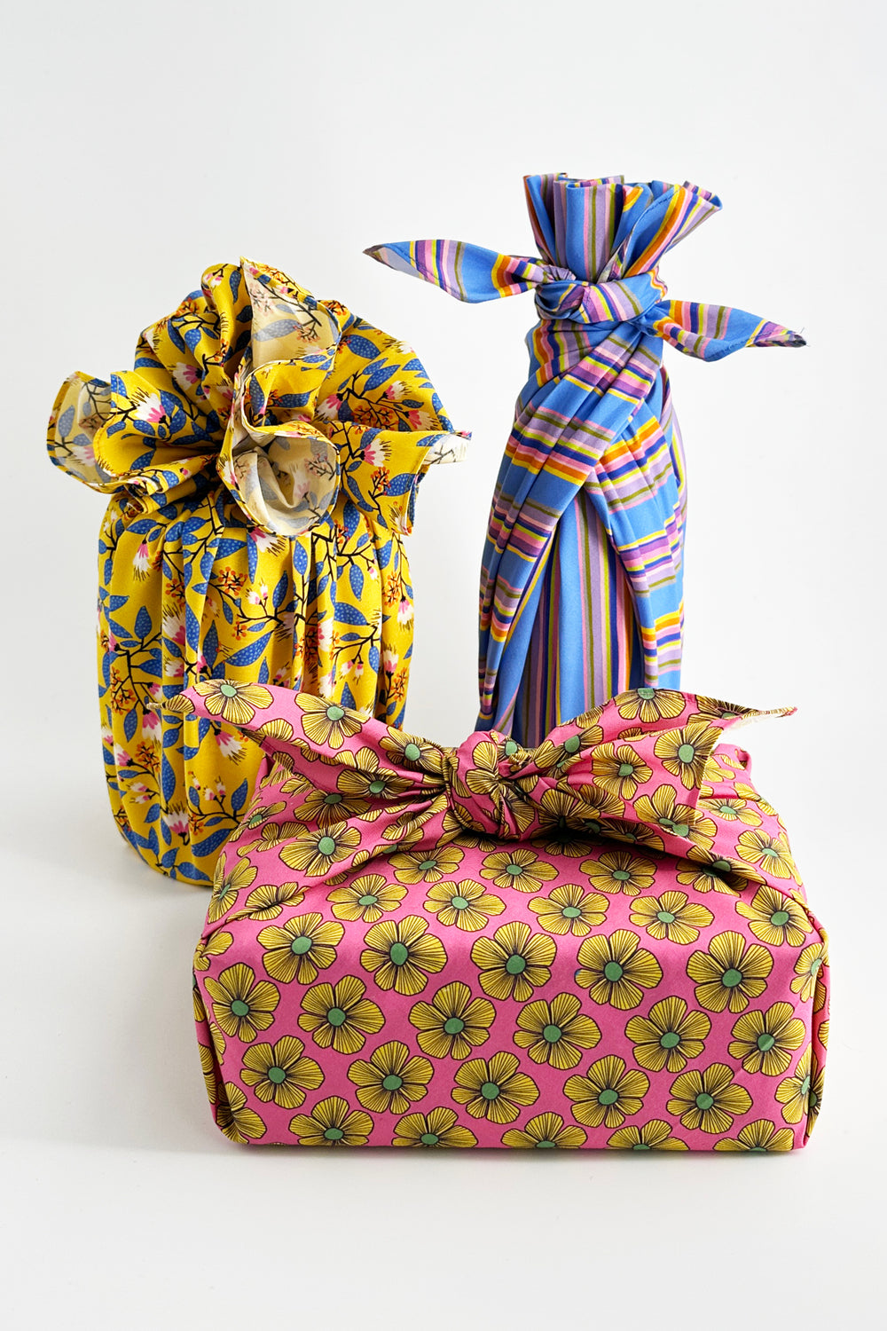 furoshiki wrapping cloth tied around objects in blue stripe and yellow floral patterns