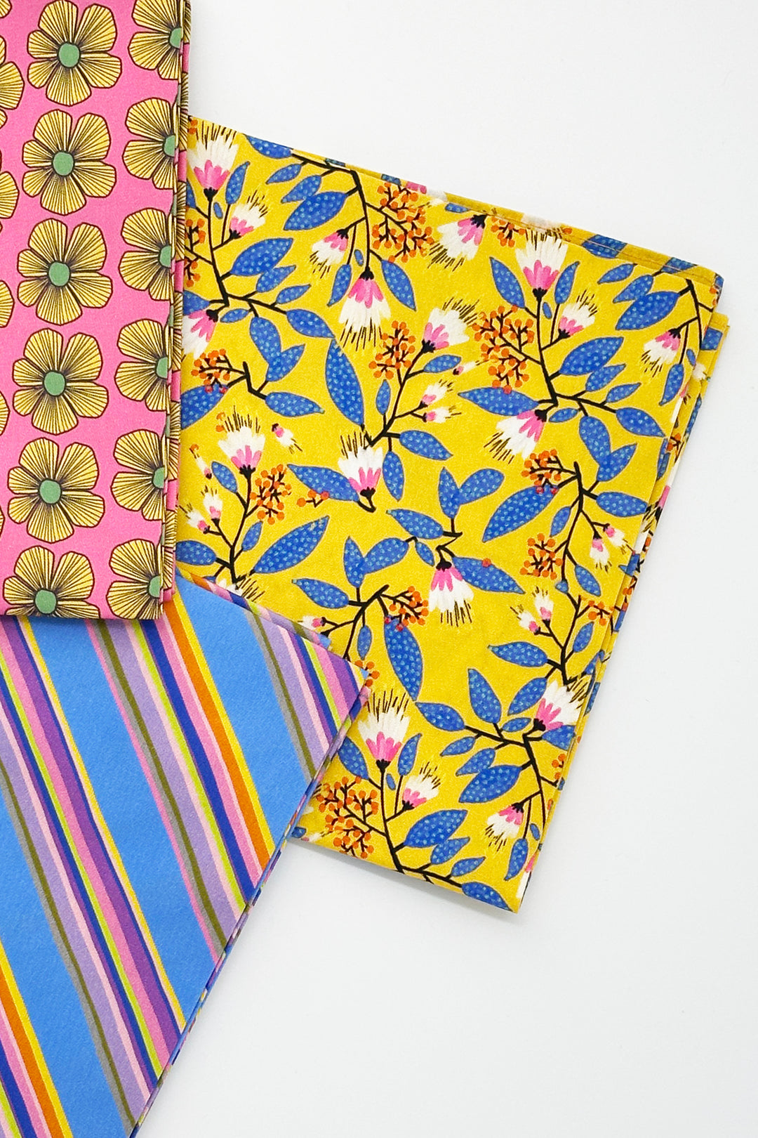 folded furoshiki wrapping cloth with yellow floral print next to blue striped cloth
