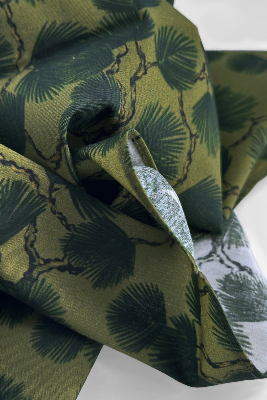 folded furoshiki wrapping cloth showing pine branch print in deep green tones