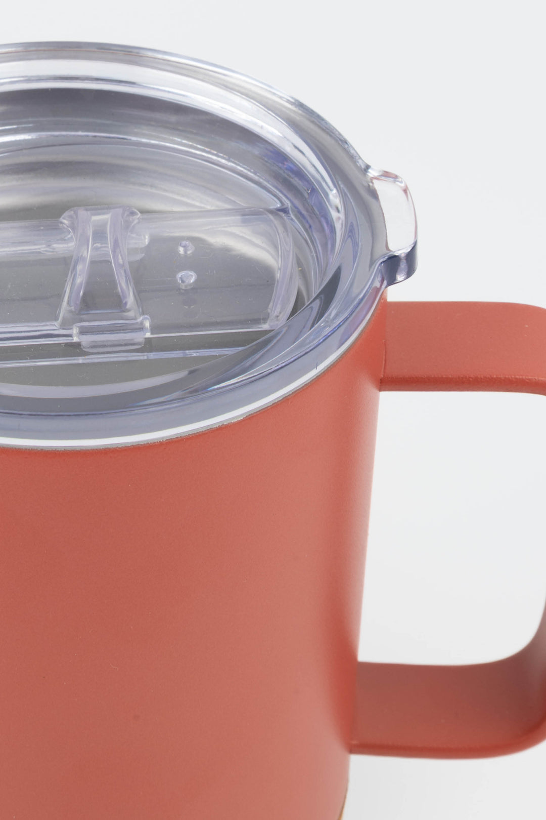 close up of clear lid and handle on red insulated mug with cork base
