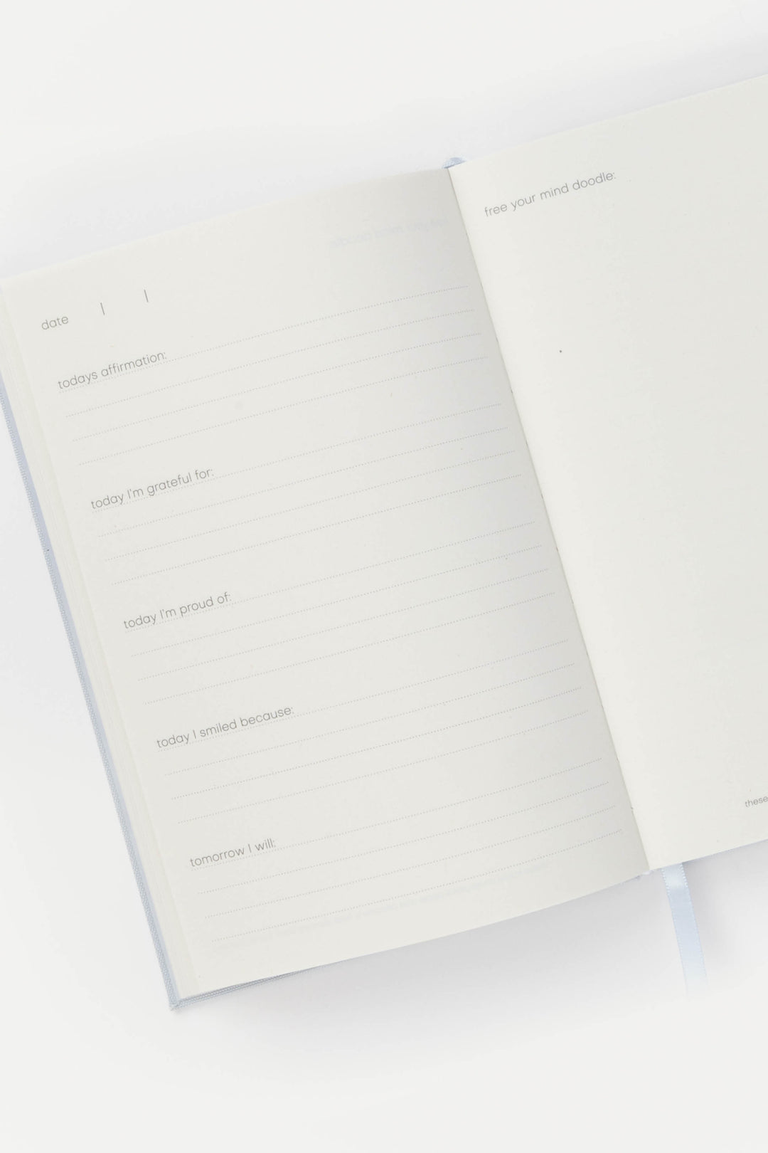 Journal opened to structured prompts, with lined pages for daily reflection and a blank doodle page on the right.