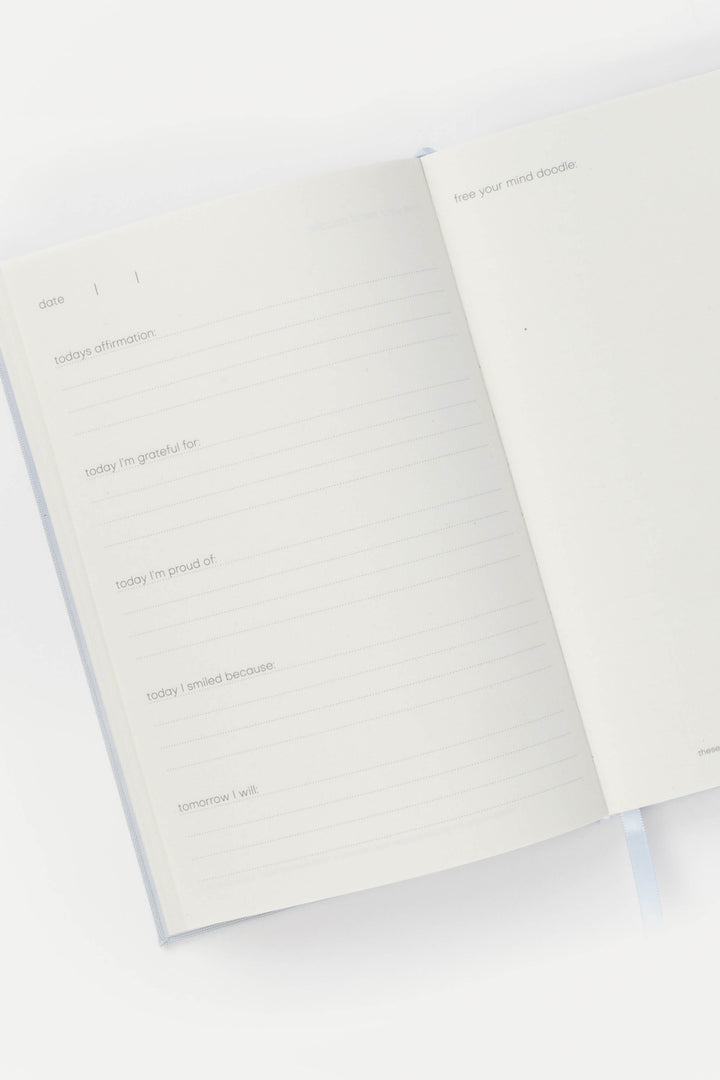 Journal opened to structured prompts, with lined pages for daily reflection and a blank doodle page on the right.