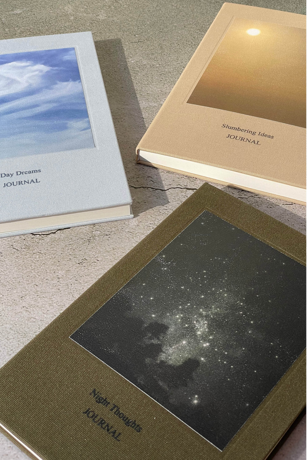 Three journals on a textured surface, each with different covers and text.