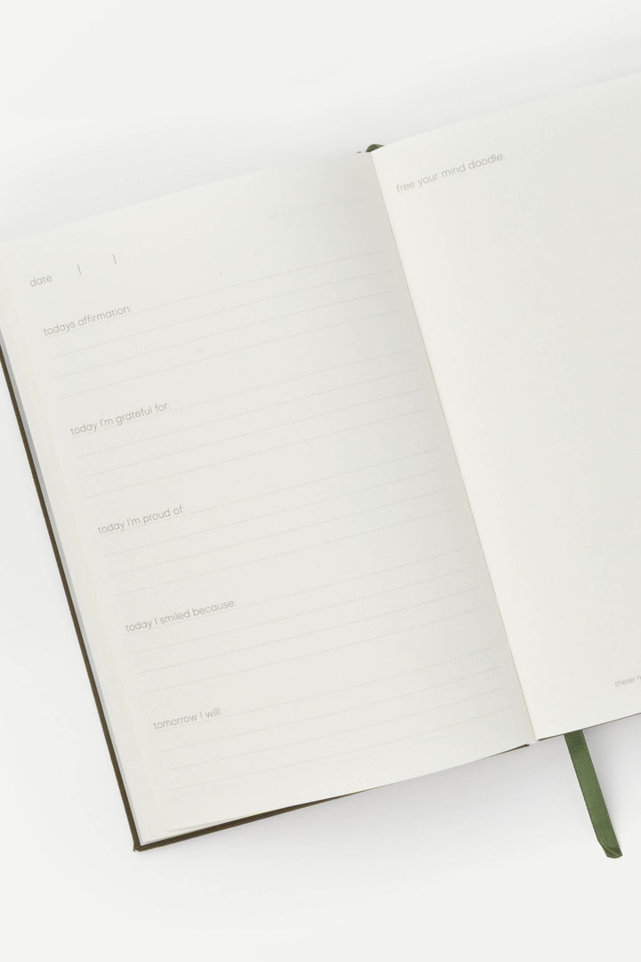 Journal opened to structured prompts, with lined pages for daily reflection and a blank doodle page on the right.
