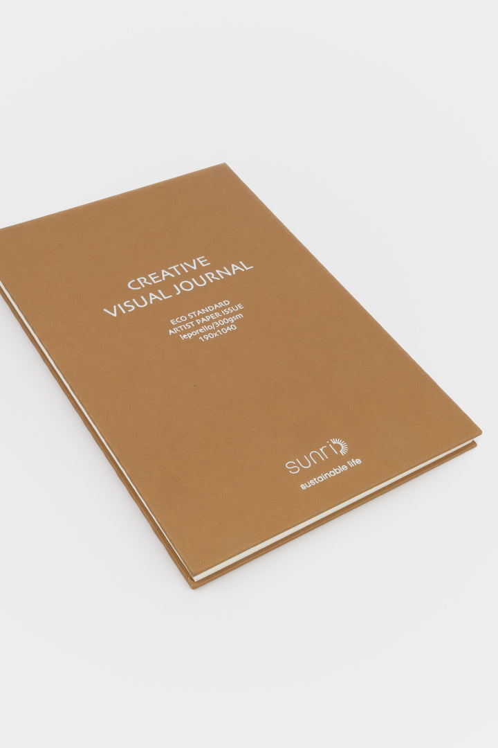 Brown journal with 'Creative Visual Journal' text on a white background