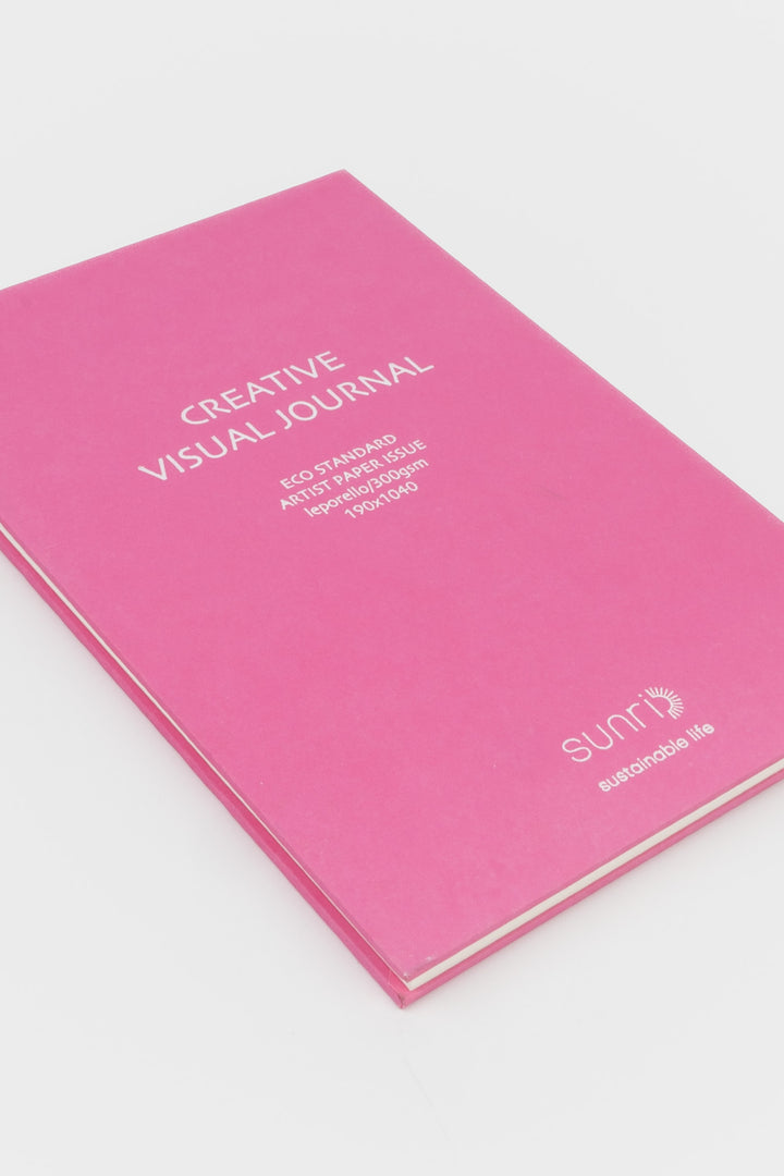 Pink journal with 'Creative Visual Journal' text on a white background