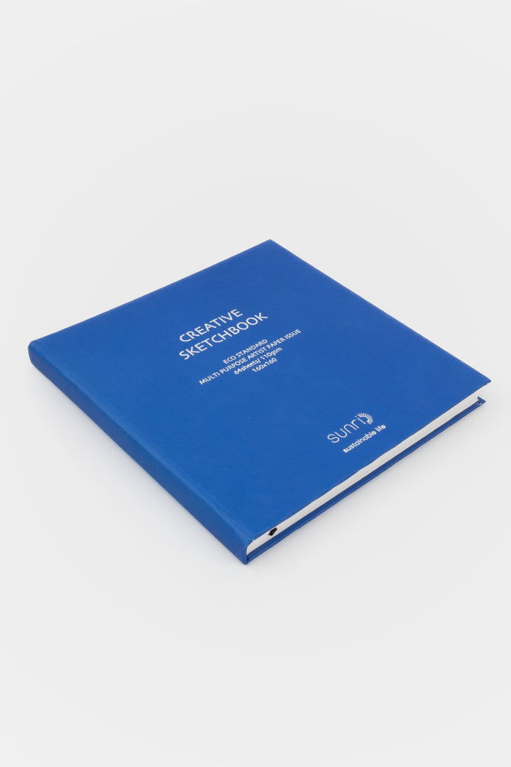 Creative square blue sketchbook with sunri branding lying closed on white background
