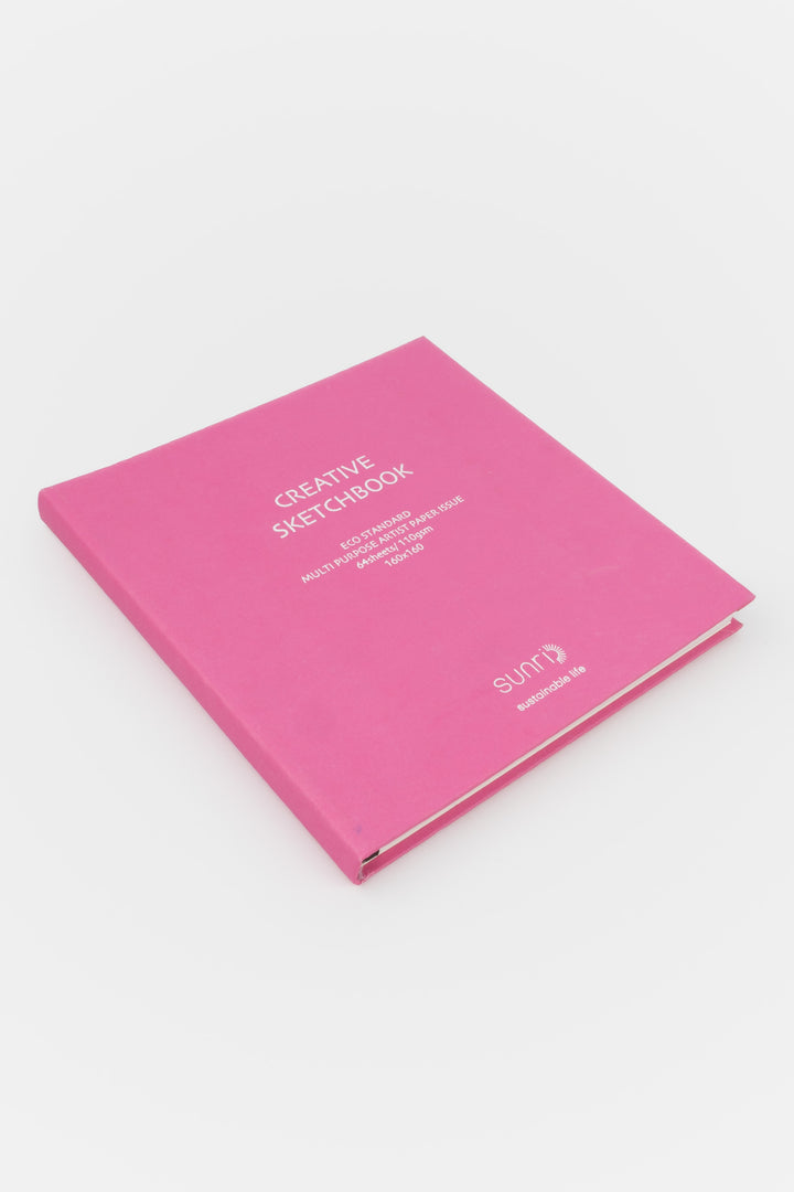 Pink notebook with 'Creative Sketchbook' text on a white background