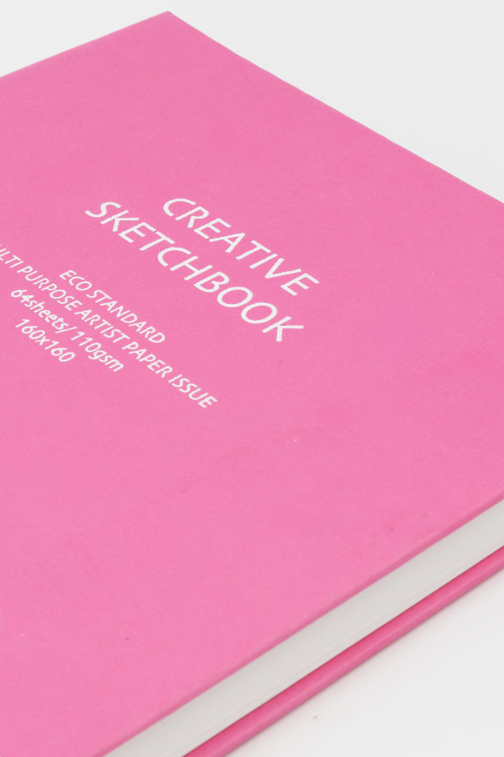 Pink sketchbook with white text on a light gray background
