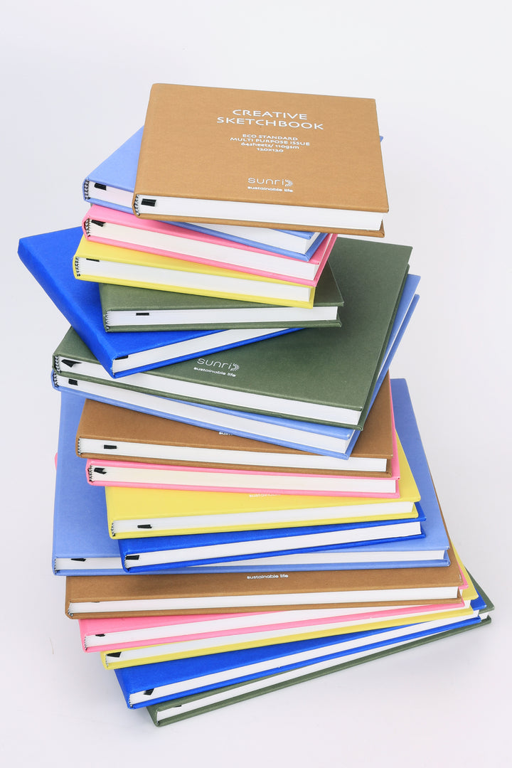Tall stack of assorted Creative Sketchbooks with yellow version visible showing white spine stitching and hardcover edges