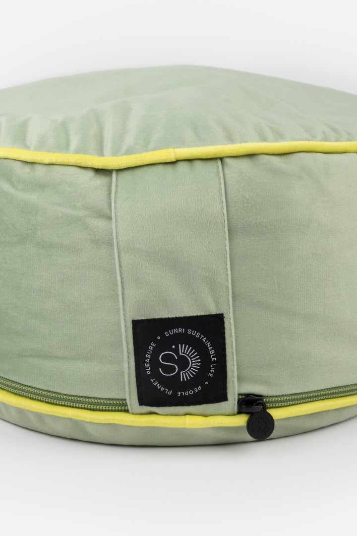 Green meditation pillow with yellow trim and a brand label on a white background