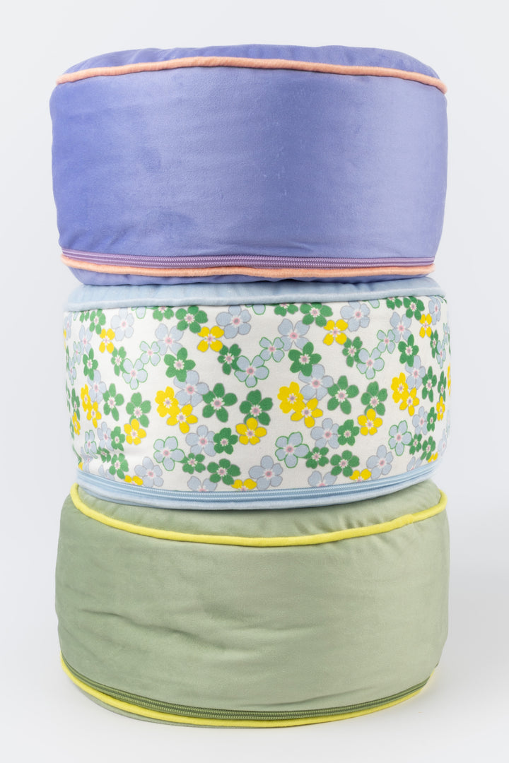 Stack of three meditation pillows with floral pattern on a white background
